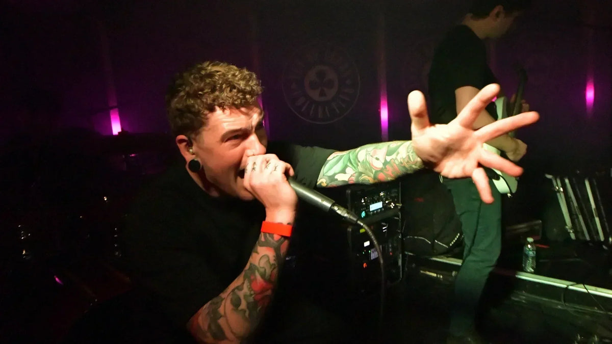 Severed Tongues vocalist Will Hagan singing into a microphone and reaching towards the crowd at TOCstock.