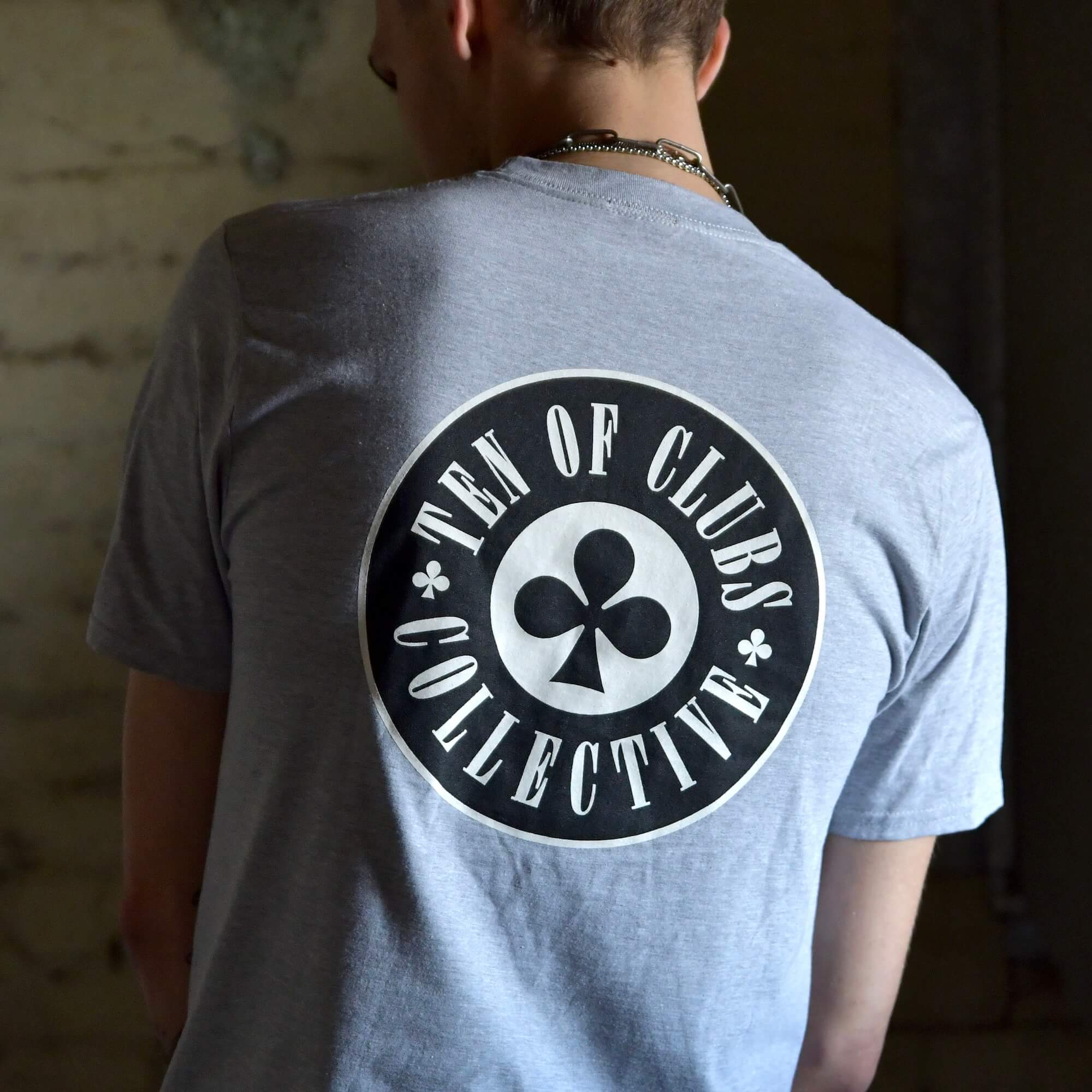 Model wearing Gunslinger Tee grey graphic t-shirt with TEN OF CLUBS COLLECTIVE logo back print | alt streetwear by TEN OF CLUBS