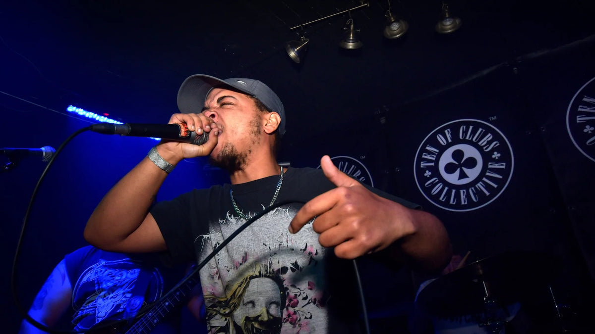 Knifepoint’s vocalist gripping a microphone during their set at TOC @ The Wheatsheaf, with blue stage lighting and a TEN OF CLUBS backdrop.