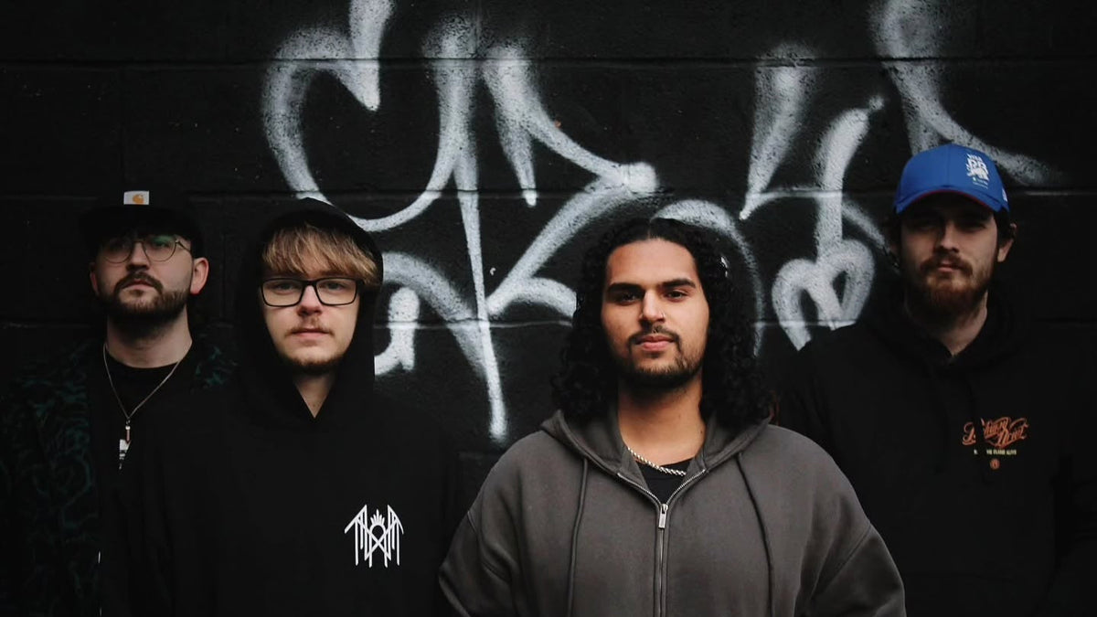 In Absentia band members standing in front of a black-and-white graffiti wall.