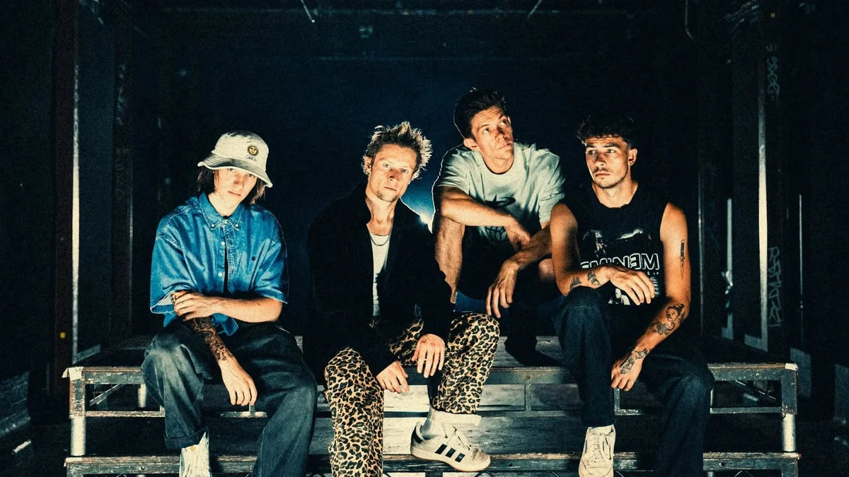 The four members of nu metal band Profiler sitting on a metal stage platform in a dark venue.